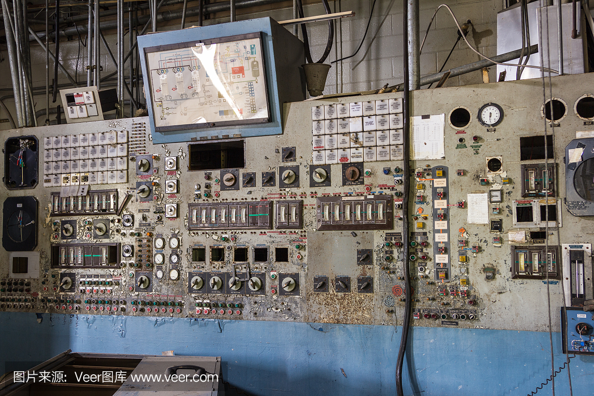 在一个废弃的工厂里,一个旧的工业机器上有一长墙的仪表和开关